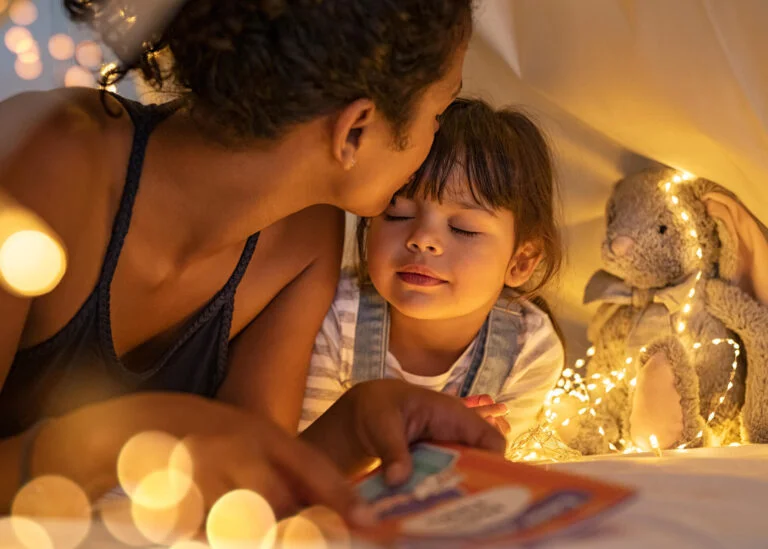 mother kissing daughter good night