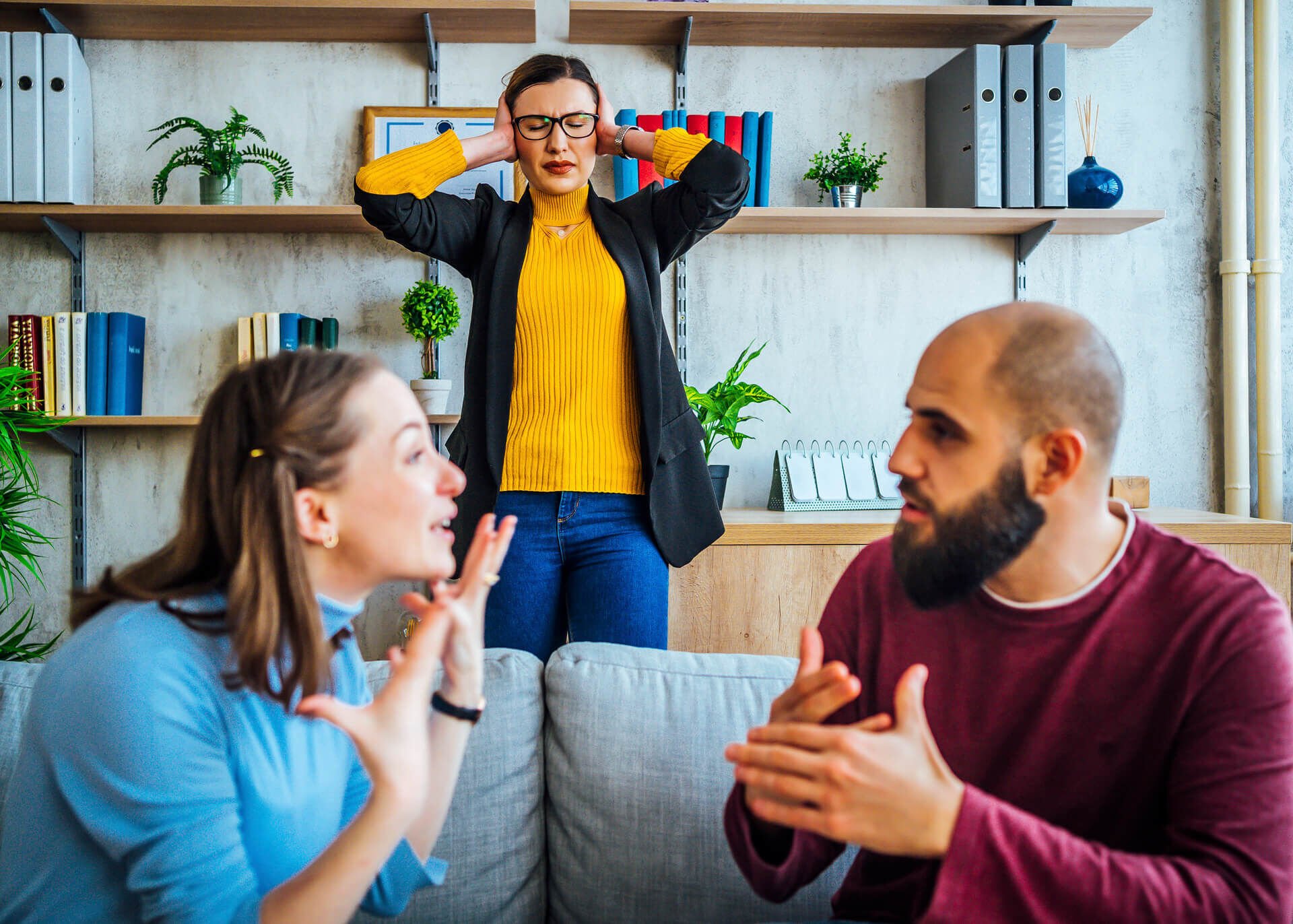 woman covering her ears while two people are arguing