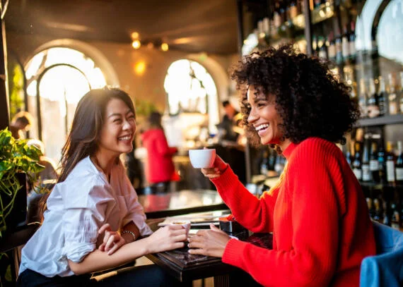 two female friends laughing in a cafe