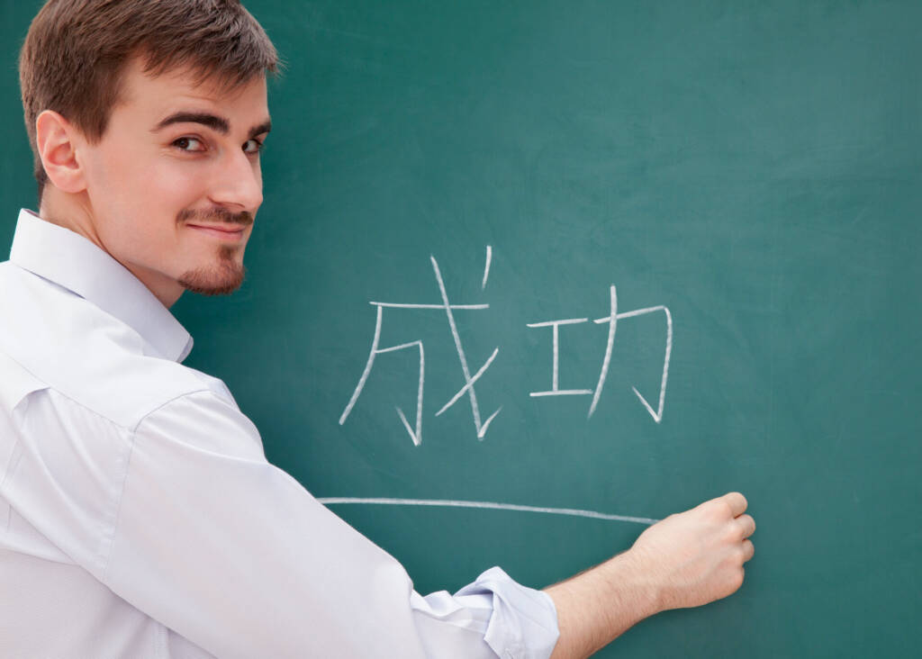 young man writing chinese on blackboard