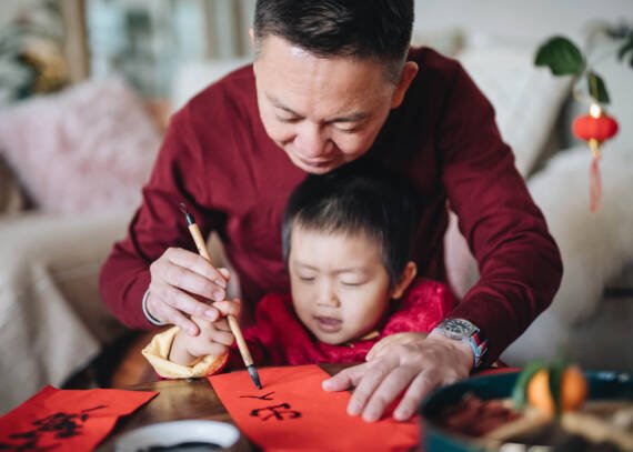 father teaching son to write chinese characters