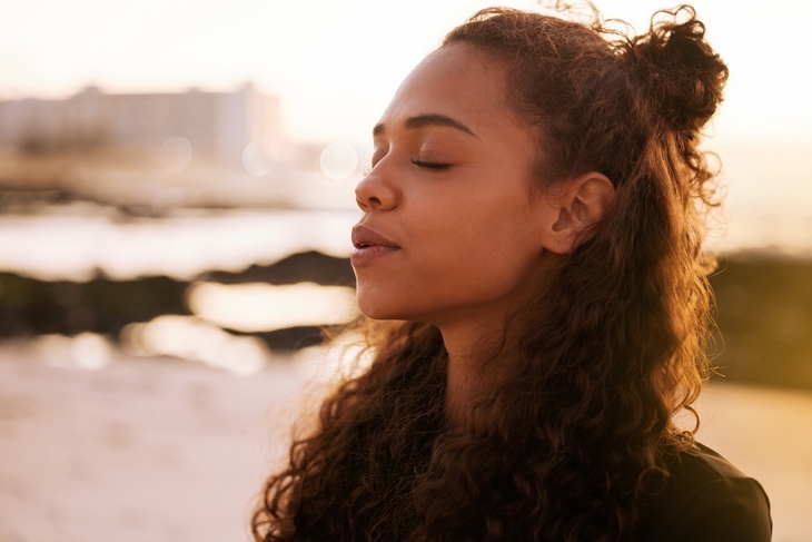 young-woman-sitting alone-and-meditating-on-the-beach-at-sunset